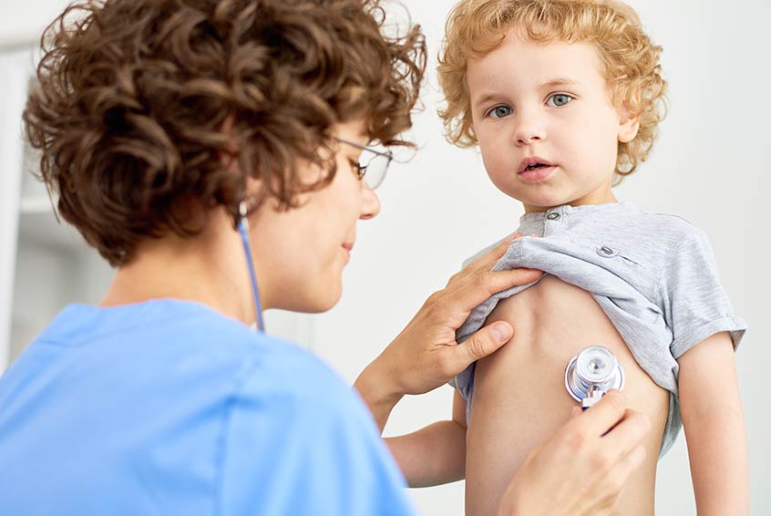 Doctor checking young childs breathing.